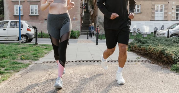 Fit couple jogging together on an urban sidewalk in sportswear.