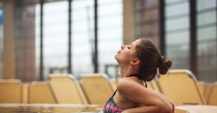 Woman relaxing in a jacuzzi at an indoor resort, enjoying leisure time.